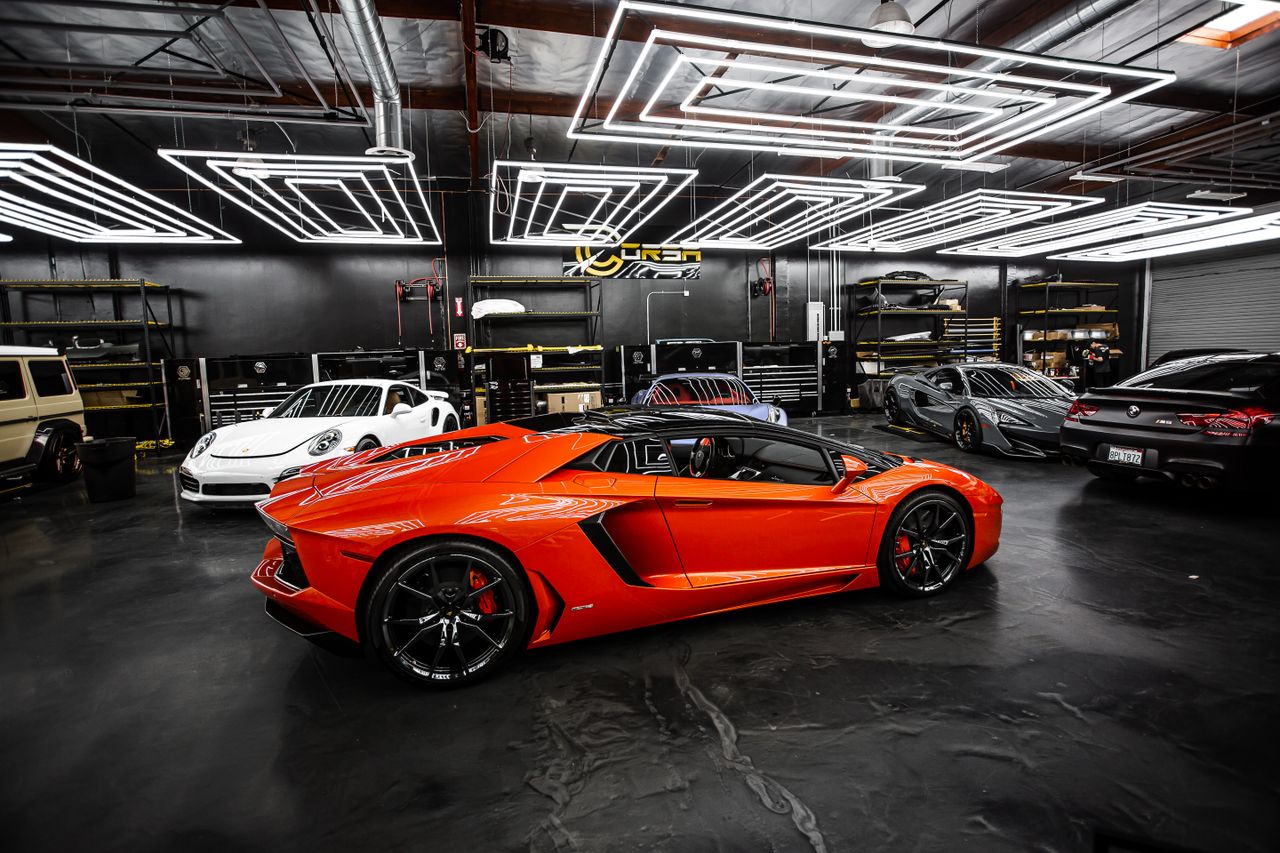 High-end sports cars displayed in a sleek, modern showroom with stylish lighting.